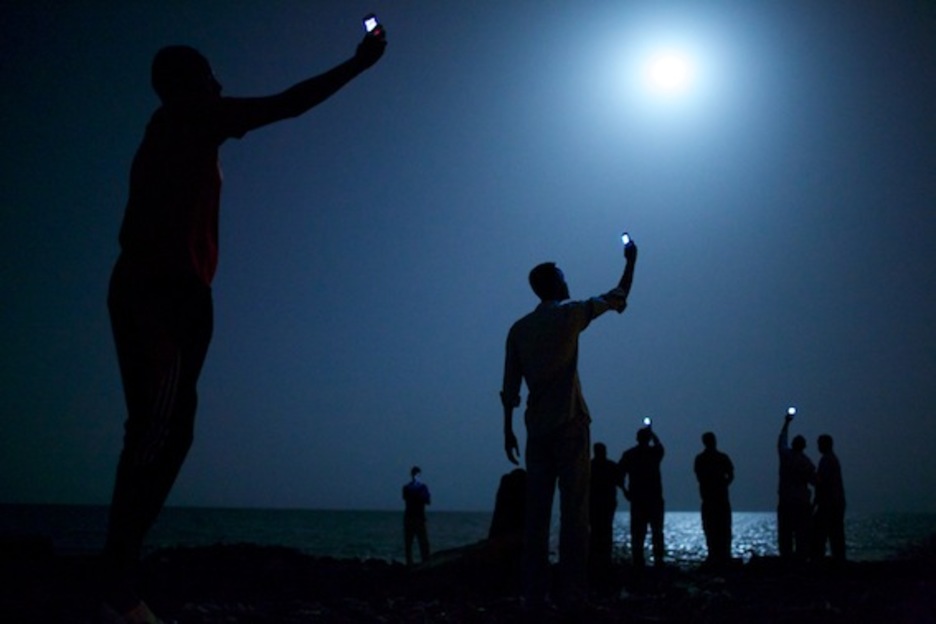 Esta imagen de inmigrantes africanos en la ciudad de Djibouti intentando captar cobertura para sus móviles para hablar con sus familiares ha sido galardonada con el World Press Photo 2013. (John STANMEYER)
