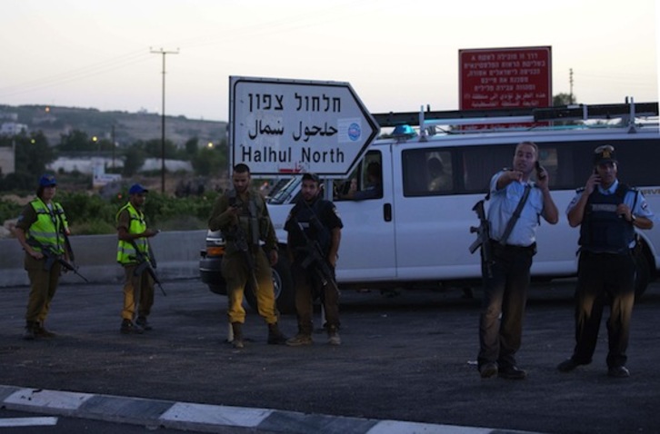 Soldados y policías israelíes, en las inmediaciones del lugar donde han hallado los cadáveres. (Menahem KAHANA/AFP PHOTO)