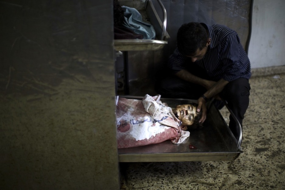Un hombre observa en una morgue el cuerpo sin vida de un niño muerto por el ataque israelí. (Mahmud HAMS/AFP)