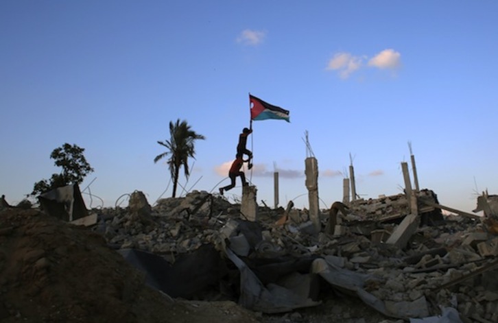 Dos niños, con una bandera palestina entre los escombros de Gaza. (Said KHATIB/AFP PHOTO)