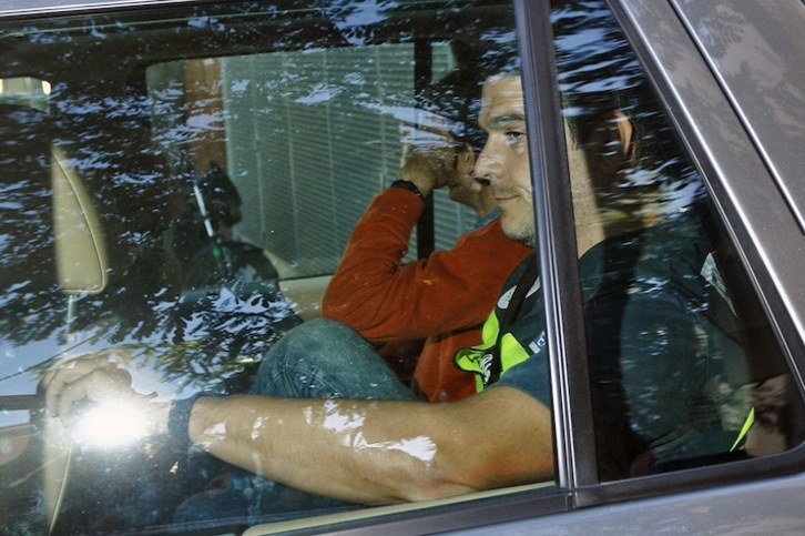 Oleguer Pujol se tapa el rostro en el vehículo policial en el que ha sido trasladado a comisaría. (Quique GARCÍA/AFP)
