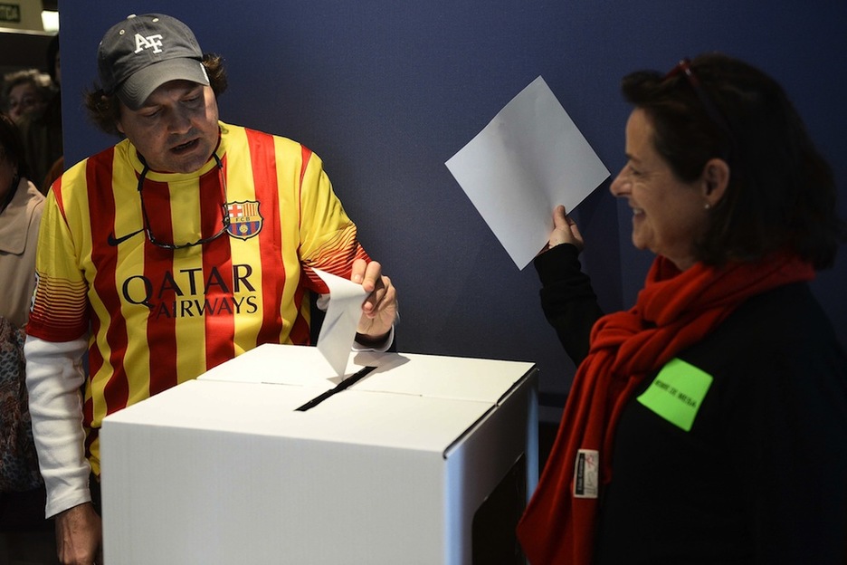 Un hombre ataviado con la camiseta del Barça deposita su voto. (Lluis GENE/AFP) 