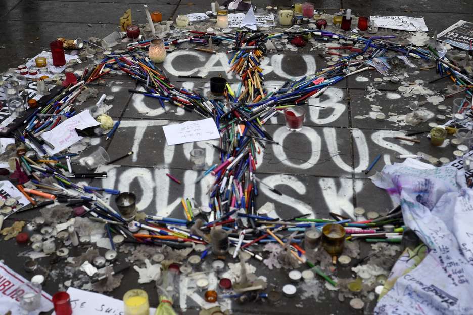 Lápices y bolígrafos dibujan el símbolo de la paz sobre los nombres de algunos de los dibujantes muertos. (Martin BUREAU/AFP PHOTO)