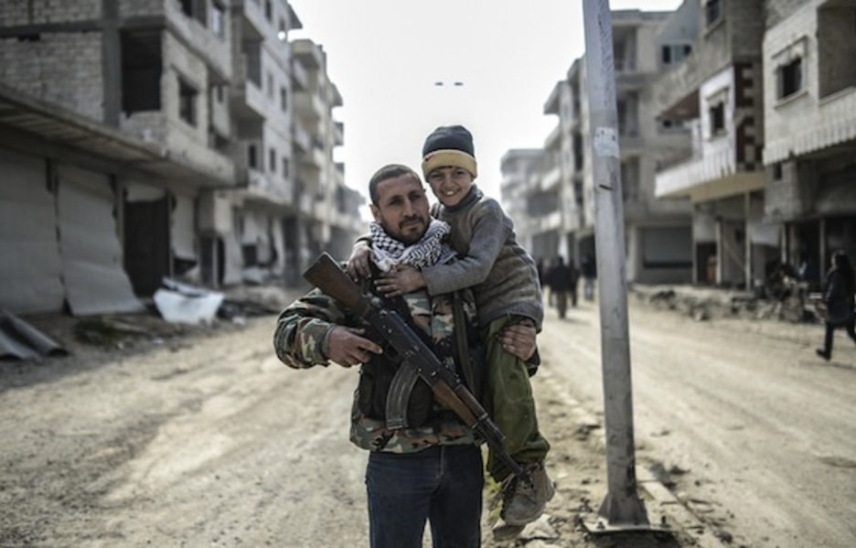 Un combatiente kurdo con su hijo en brazos. (Bulent KILIC/AFP PHOTO)