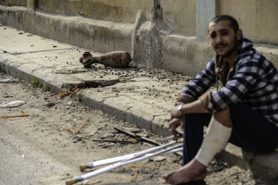 Un combatiente, herido, posa junto a un proyectil. (Bulent KILIC/AFP PHOTO)