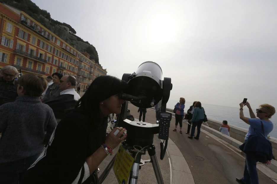 Una mujer utiliza el telescopio para poder visualizar el eclipse, en Niza. (Valery HACHE/AFP) 