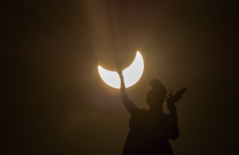 Eclipse visto junto a una estatua del Museo del Arte y de la Historia de Viena. (Joe KLAMAR/AFP)