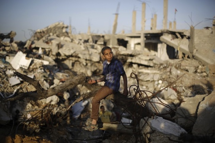 Un niño palestino, sentado sobre los escombros en Gaza. (Mohamed ABED/AFP PHOTO)