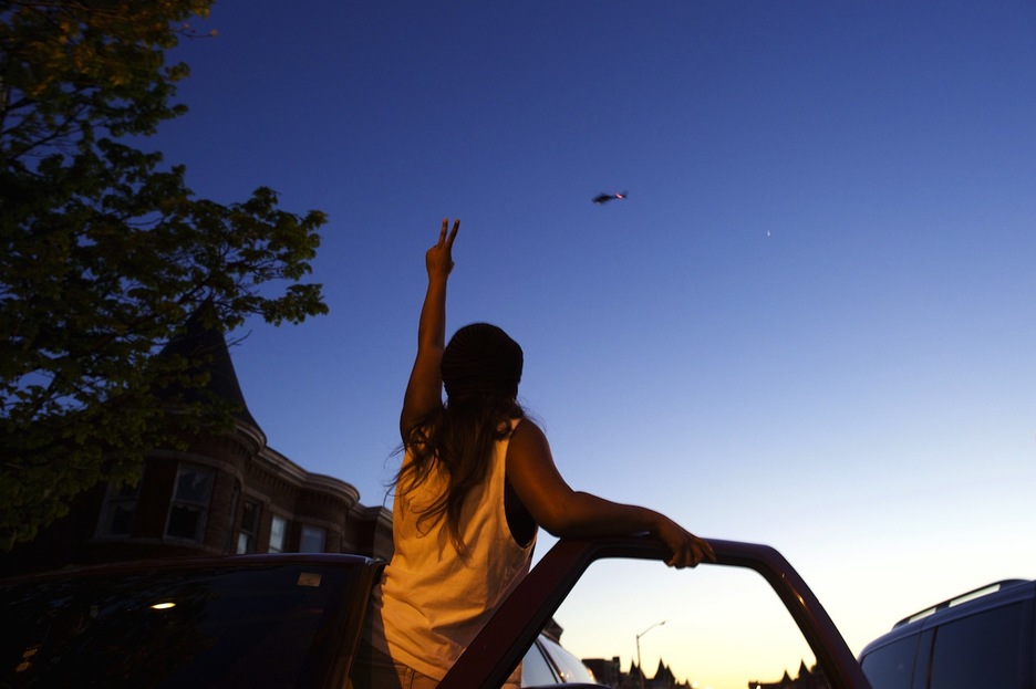 Una joven ante el helicóptero que sobrevuela Baltimore. (Mark MAKELA / AFP)