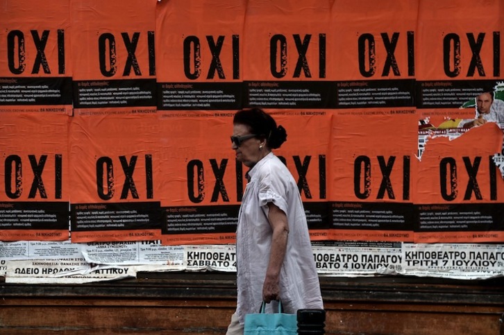 Una mujer pasa ante unos carteles que piden votar «no» en el referéndum. (Aris MESSINIS/AFP) 