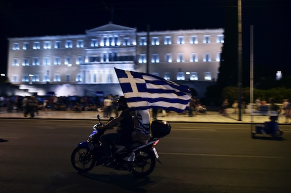 Un motoclista porta una bandera griega. (Aris MESSINIS/AFP PHOTO)