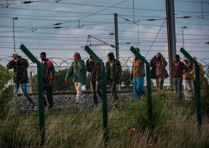 Migrantes que han logrado acceder a la terminal del Eurotúnel caminan junto a las vías del tren. (Philippe HUGUEN/AFP) 