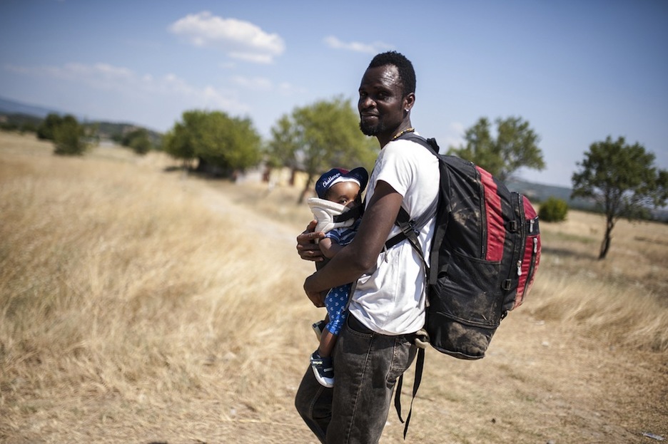 Un hombre con su hijo en brazos camina hacia Gevgelija. (Robert ATANASOVSKI/AFP)