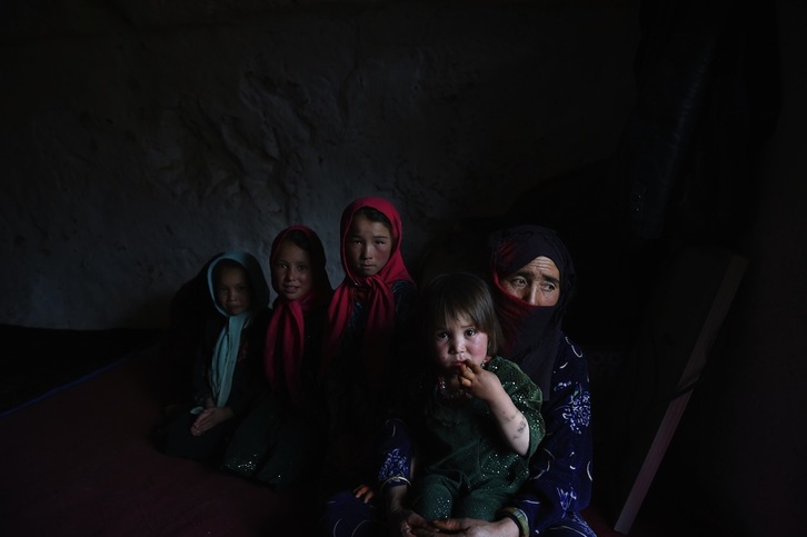 Una mujer sentada con sus hijos en su cueva en Bamiyán, a 200 kilómetros al noroeste de Kabul. (Shah MARAI/AFP) 