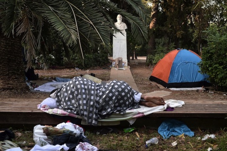 Migrantes duermen en un parque de Atenas. (Louisa GOULIAMAKI/AFP PHOTO)