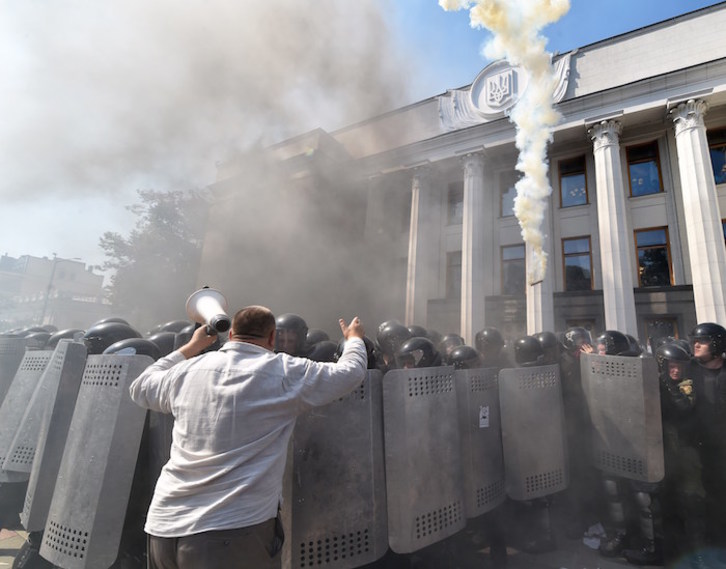 Manifestantes, humo y policías frente al Parlamento en Kiev. (Sergei SUPINSKY | AFP)