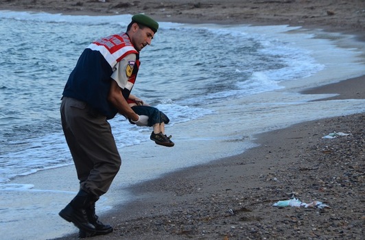 Un policía turco traslada el cadáver de Aylan Kurdi en la playa de Bodrum. (Nilufer DEMIR/AFP)