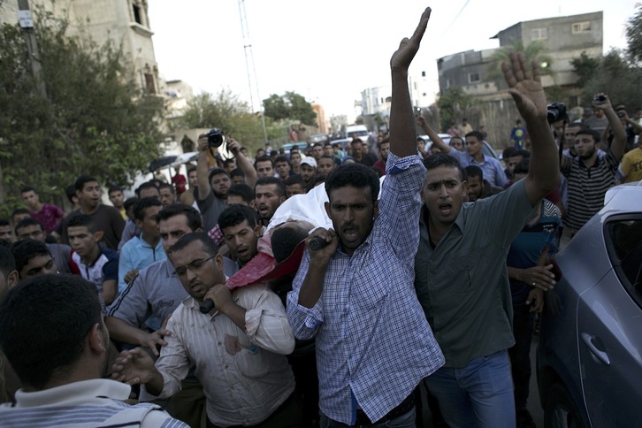 Ciudadanos transportan a un joven palestino de 21 años, muerto por disparos de Israel. (Said KHATIB / AFP)