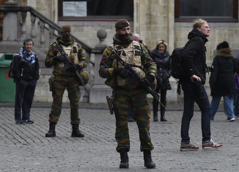 Militares con armas en mano en Grand Place, mientras algunos turistas siguen su curso (John THYS | AFP)