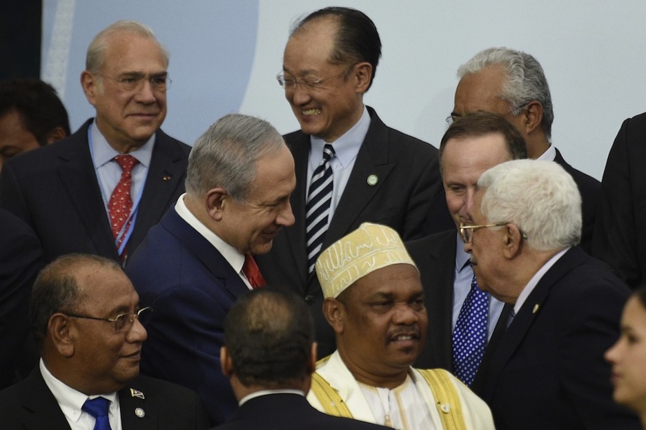 Benjamin Netanyahu, primer ministro israelí, se saluda con el presidente palestino Mahmud Abbas. (Martin BUREAU / AFP)