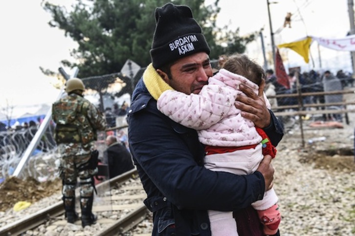 Un hombre llora al cruzar, con su hija en brazos, la frontera entre Grecia y Macedonia. (Armend NIMANI/AFP)