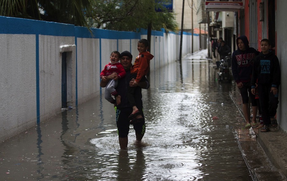 Un hombre lleva a dos menores en las calles inundadas. (Said KHATIB / AFP)