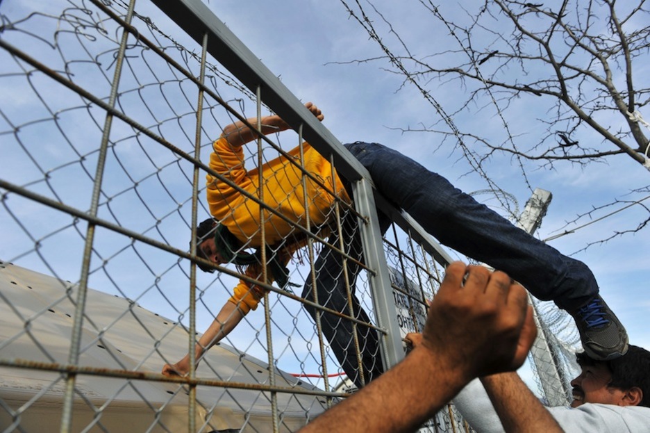 Un refugiado trata de saltar la valla fronteriza entre Grecia y Macedonia. (SAKIS MITROLIDIS / AFP)