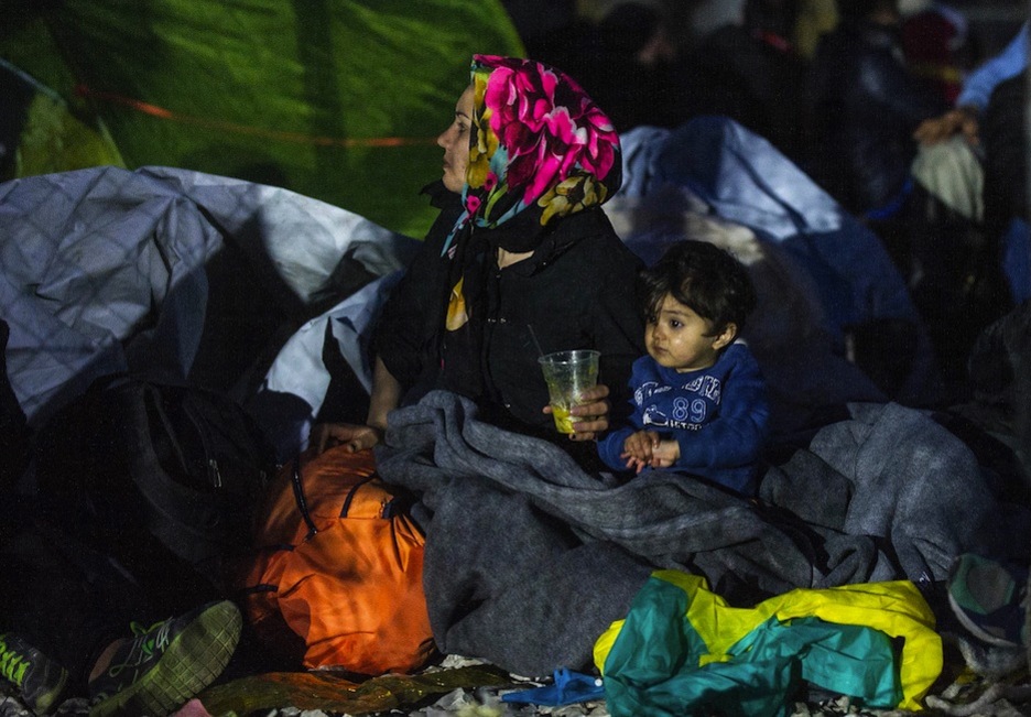 Una mujer y un niño aguardan para intentar cruzar la frontera en Gevgelija. (ROBERT ATANASOVSKI / AFP)   