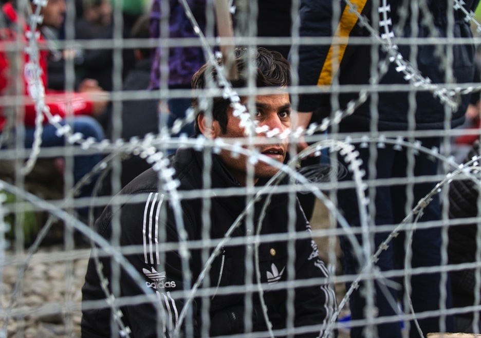 Un refugiado afgano dirige su mirada al otro lado de la valla. (ROBERT ATANASOVSKI / AFP)