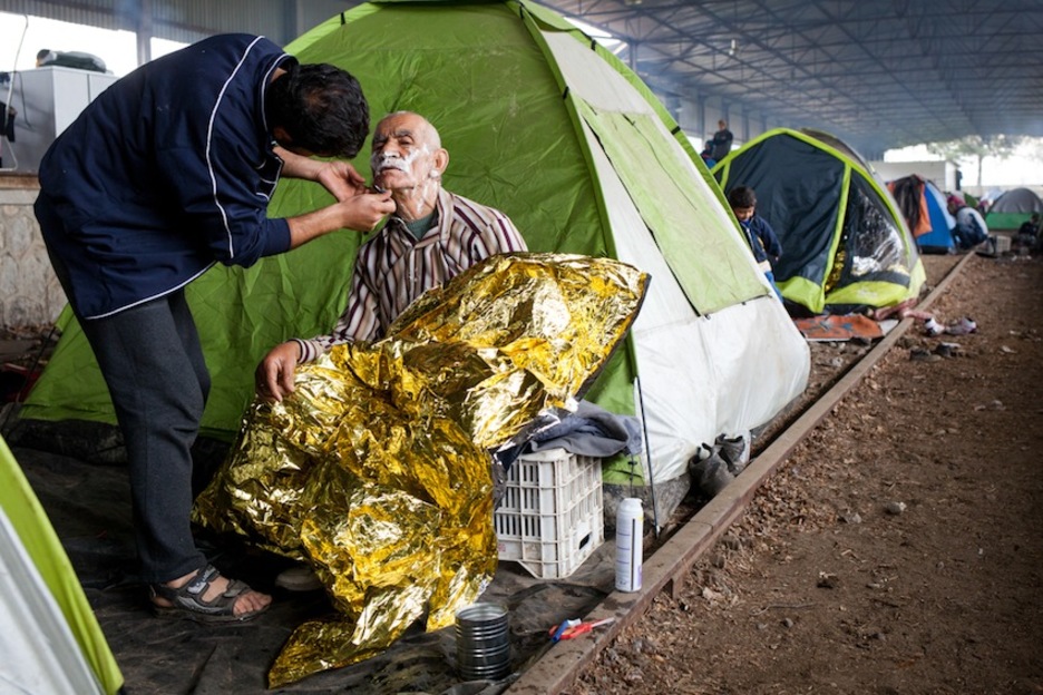 Un anciano es afeitado en un andén de tren abandonado reconvertido en refugio. (Juan TEIXEIRA)