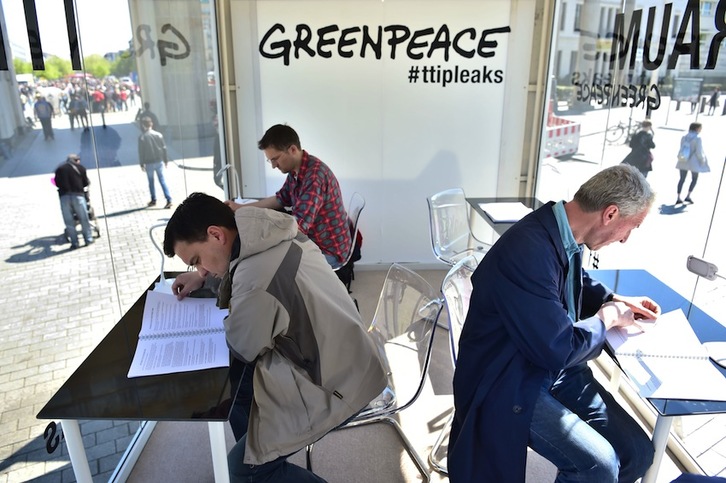 Varias personas consultan en Berlín los documentos sobre el TTIP revelados por Greenpeace. (John MACDOUGALL/APF) 