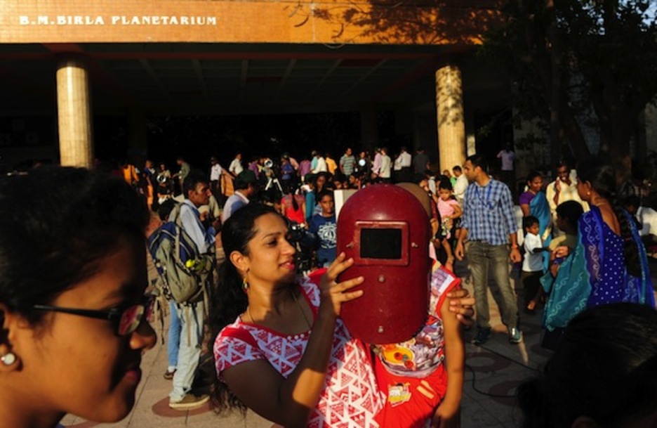 Una mujer coloca frente a su hija una máscara de soldador para que esta siga el paseo de Mercurio frente al Sol, en Chennai (India). (Arun SANKAR/AFP)
