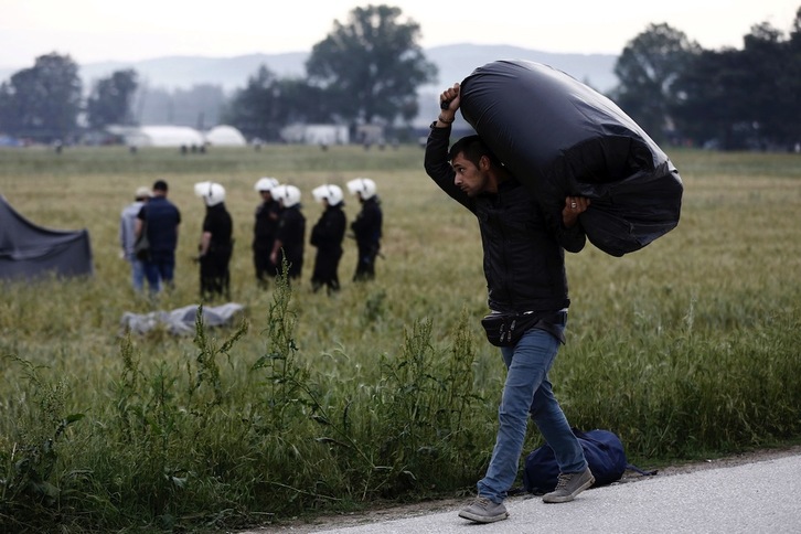 Un refugiado recoge sus pertenencias mientras la Policía desaloja a más albergados. (Yannis KOLESIDIS / AFP)
