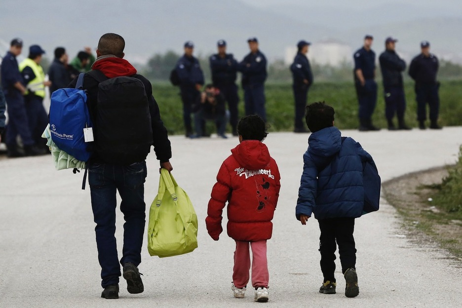 Un hombre, junto a dos menores, abandonan Idomeni. (Yannis KOLESIDIS / AFP)