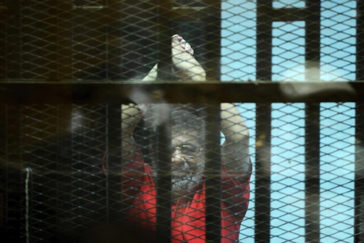 Mohamed Morsi levanta los brazos durante el juicio. (Mohamed EL-SHAHED/AFP)