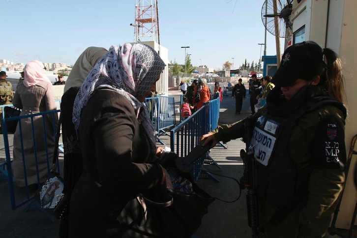 Una policía israelí registra a mujeres palestinas en un puesto de control entre Belén y Jerusalén. (Musa AL SHAER/AFP)