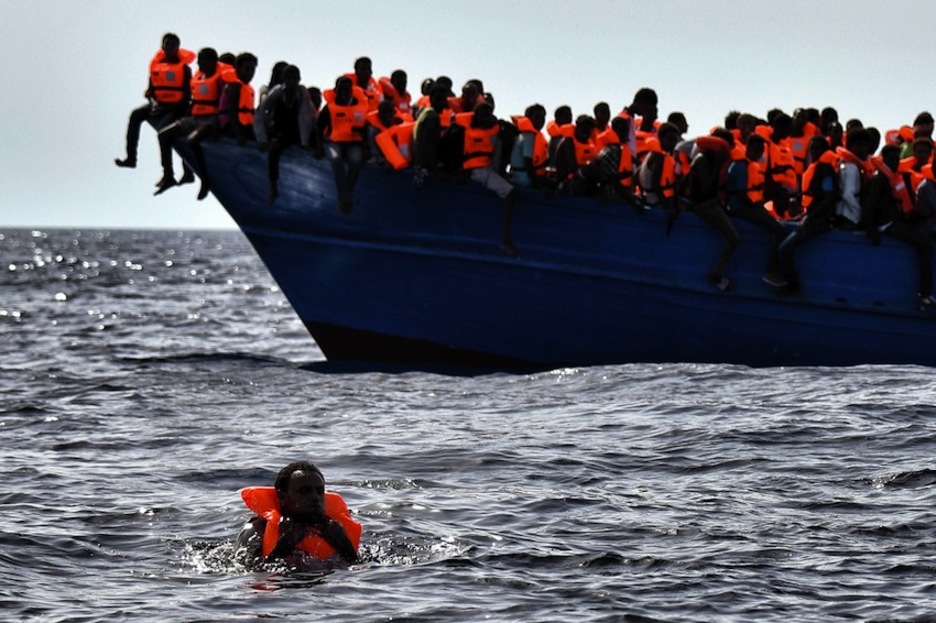 Un hombre aguarda el rescate en el agua, el resto a bordo de un barco. (Aris MESSINIS / AFP)