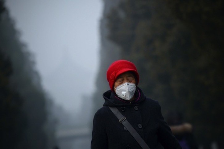 Una mujer con mascarilla camina por Pekín, una de las ciudades chinas que recientemente ha estado en alerta roja por contaminación. (Wang ZHAO/AFP)