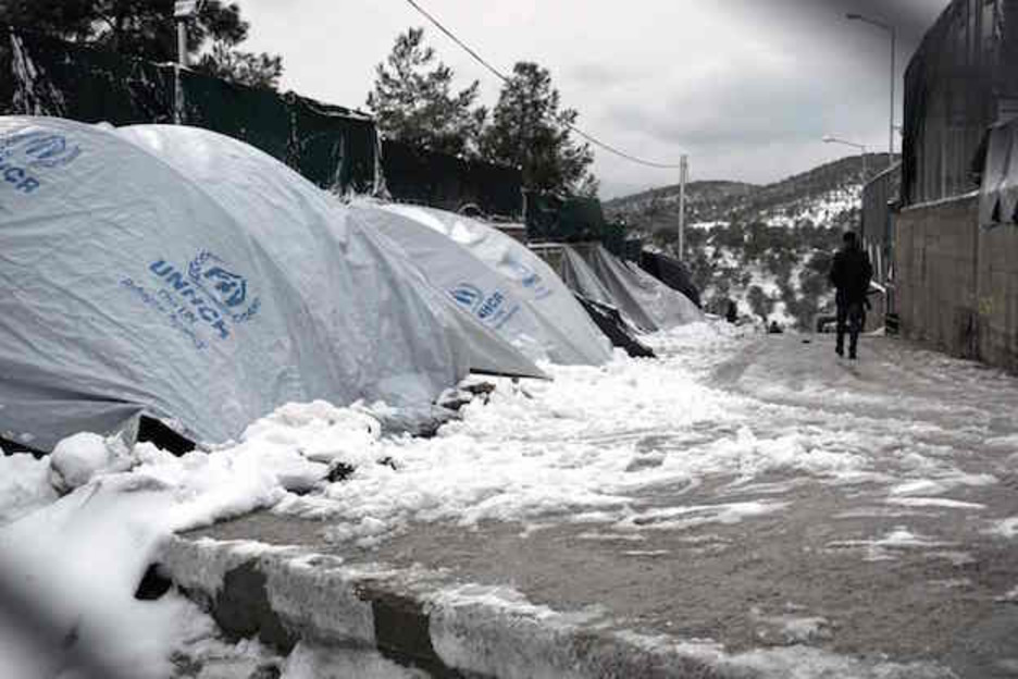 Caminando junto a las tiendas de ACNUR cubiertas por la nieve en Lesbos. (AFP PHOTO / STR)