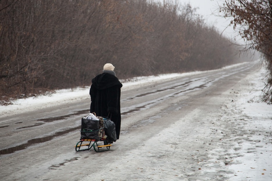 Una mujer cruza con un pequeño trineo la zona gris que separa la parte ucraniana de la de la República Popular de Donetsk (RPD). (Juan TEIXEIRA)