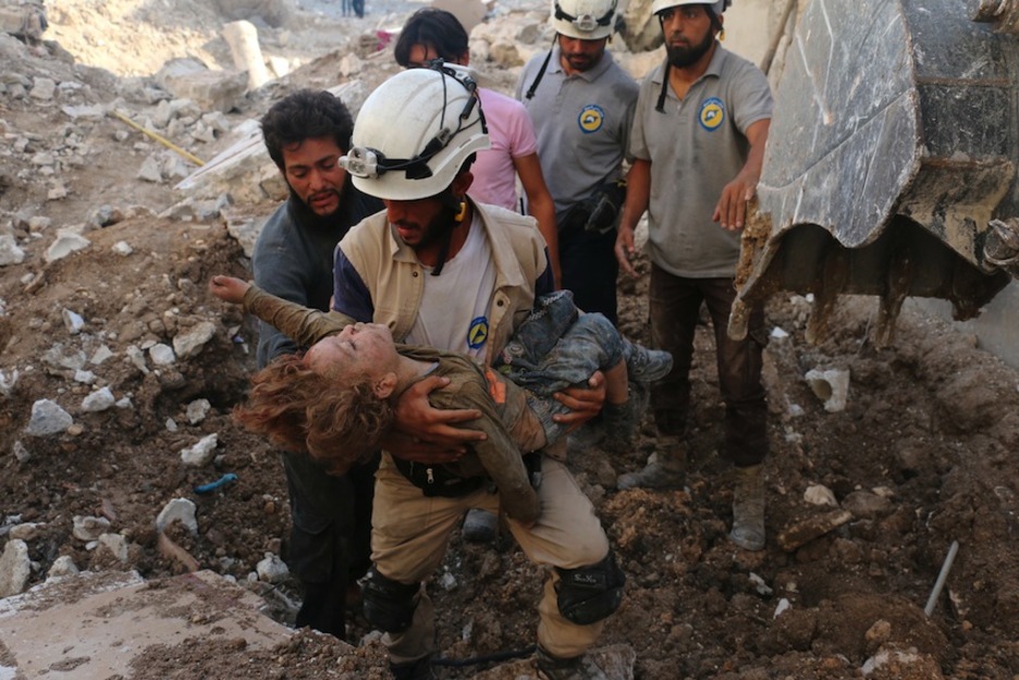 Un voluntario de defensa civil sirio sostiene a un niño en brazos tras un ataque en Alepo.  (Ameer ALHALBI/AFP) 