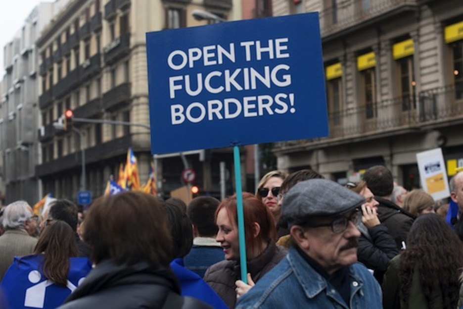 Una joven, con un cartel que exige la apertura de fronteras. (Josep LAGO/AFP)