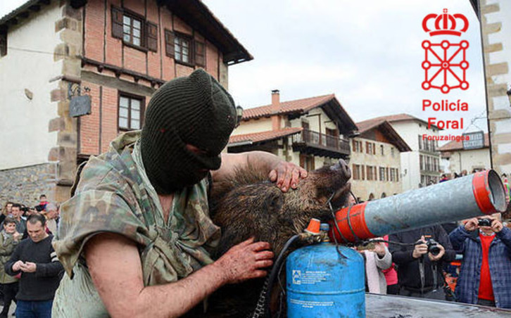 Uno de los participantes en el carnaval, con el cadáver de un jabalí. (Policía Foral)