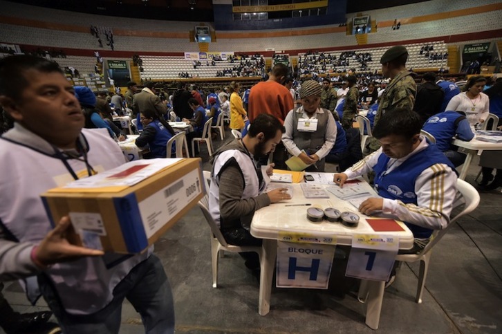Trabajadores del Consejo Nacional Electoral de Ecuador realizan el segundo recuento de votos. (Rodrigo BUENDIA/AFP)