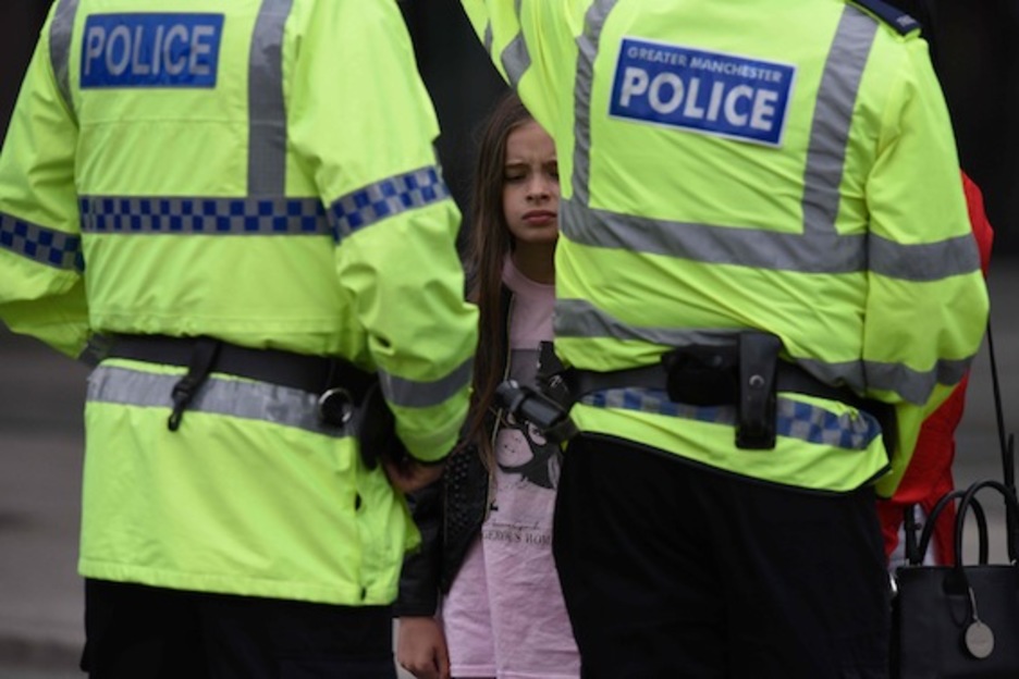 Una niña, que viste una camiseta de Ariana Grande, y su madre hablan con la Policía en las inmediaciones del Manchester Arena. (Oli SCARF/AFP)
