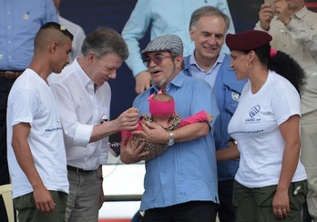 Juan Manuel Santos saluda al bebé que sostiene ‘Timochenko’. (Raúl ARBOLEDA/AFP)