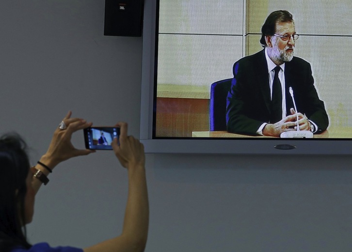Un periodista toma una imagen de la retransmsión de la comparecencia de Rajoy en la AN. (Chema MOYA-POOL/AFP PHOTO)