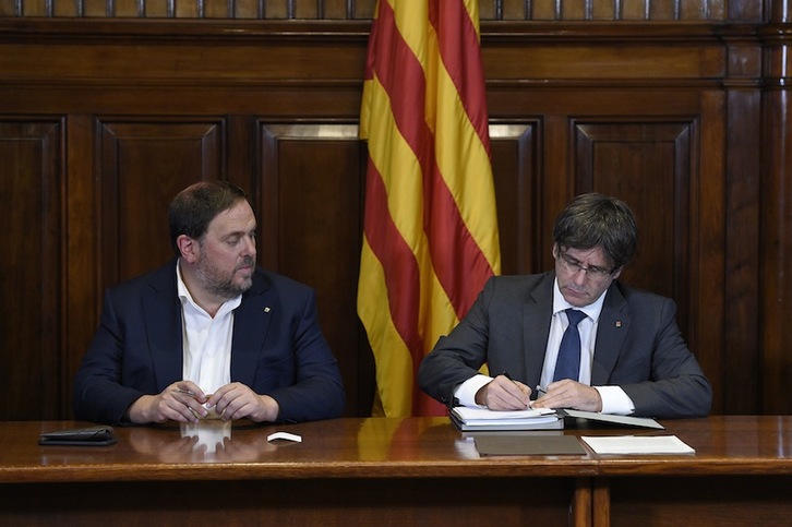 El president Carles Puigdemont firma el decreto de convocatoria dle referéndum. (Lluis GENE/AFP)