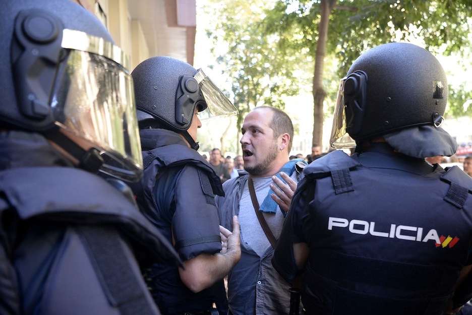 El exdiputado de la CUP David Fernández habla con los policías en el exterior de la sede del partido. (Josep LAGO/AFP)