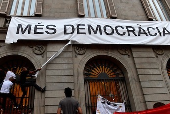 Varias personas trataron de arrancar la pancarta que colgaba de la fachada del Ayuntamiento de Barcelona tras una marcha unionista. (Josep LAGO/AFP)